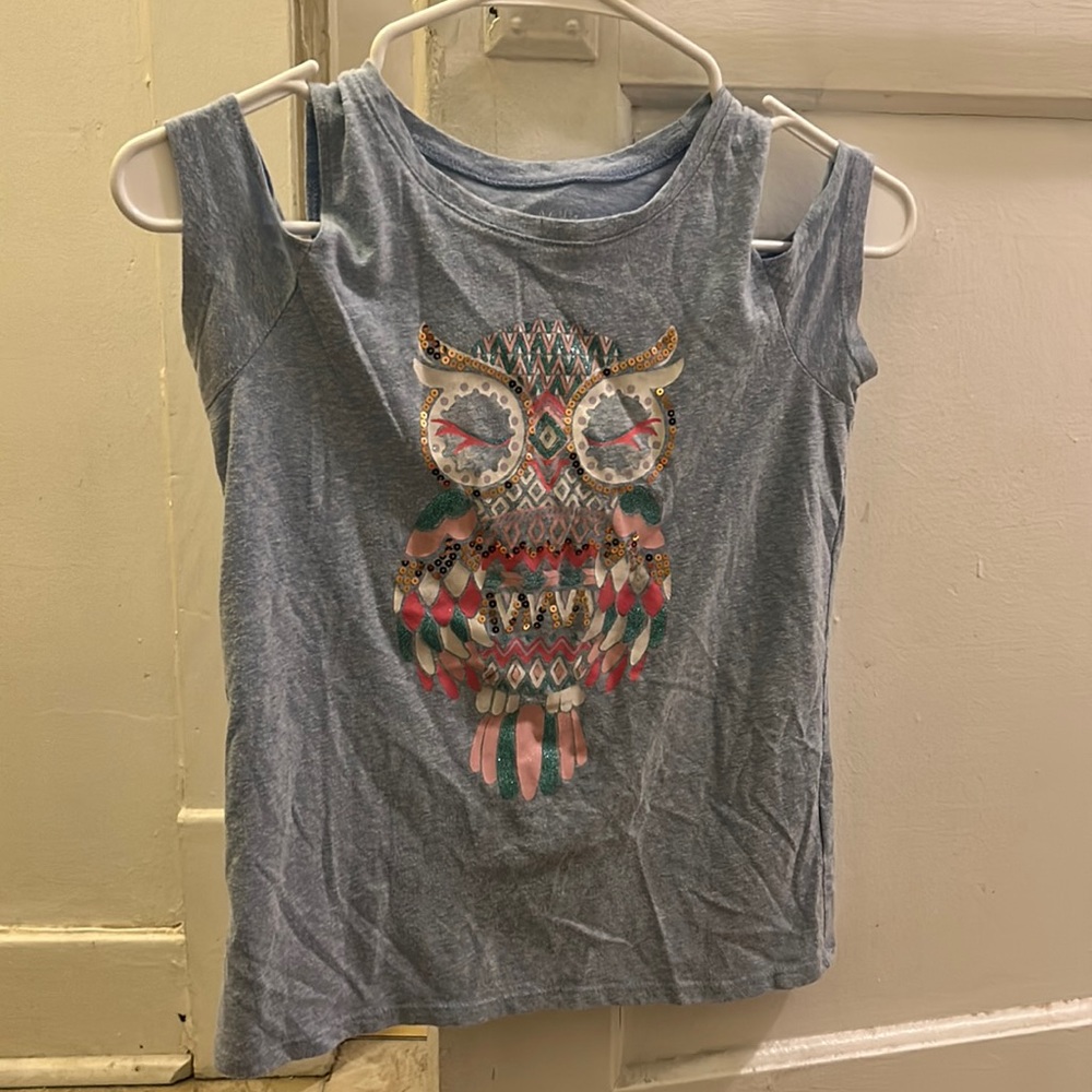 The shirt very colorful with sparkles. The shirt off the shoulder.